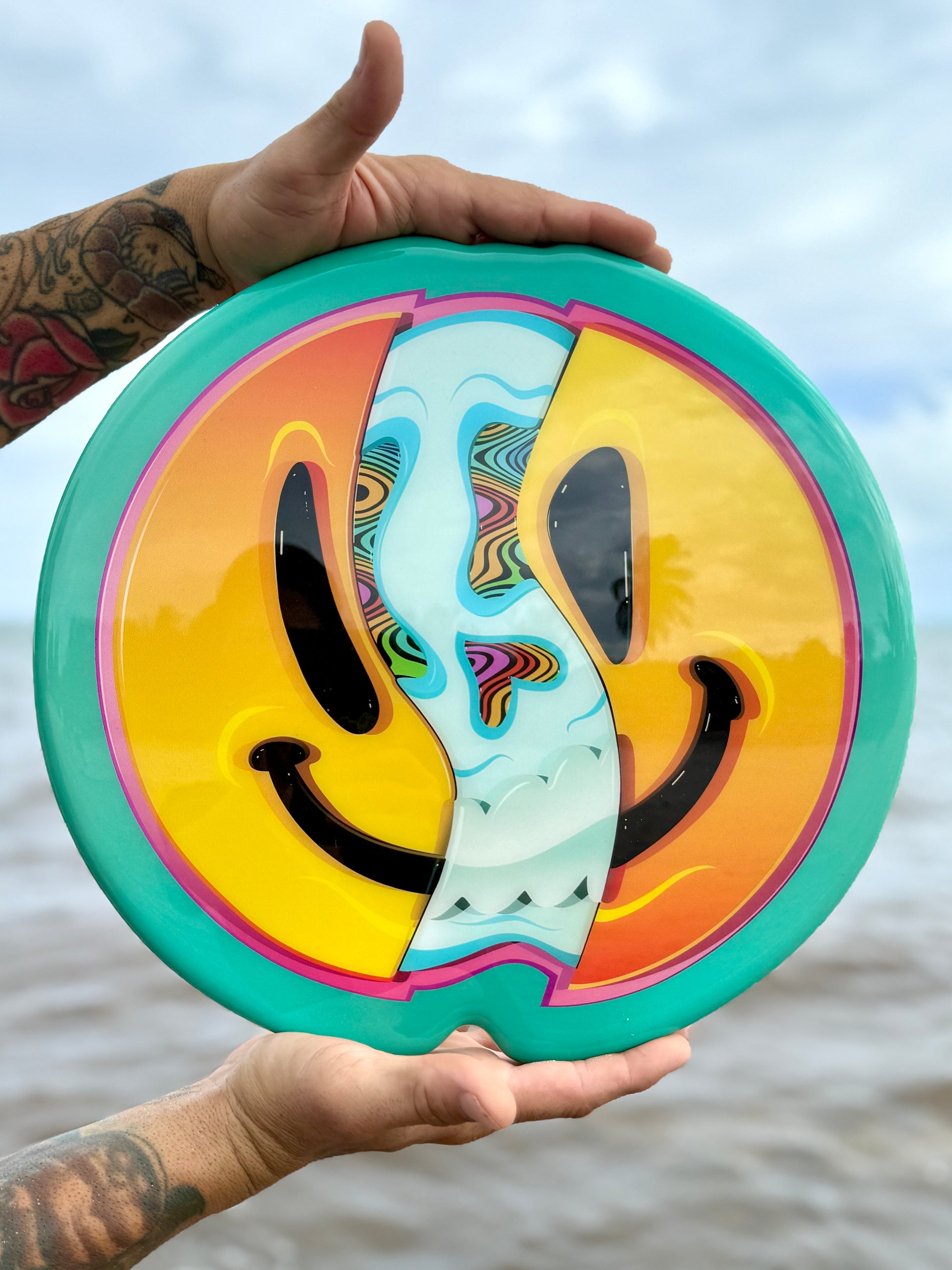 Colorful smiley face disc held by a person with a blurred natural background
